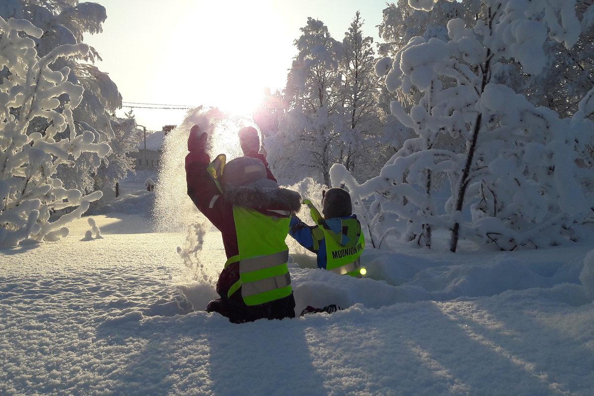Lapset leikkivät paksussa lumihangessa heitellen lunta.