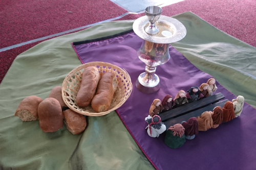 Leipää korissa, ehtoollismalja, Jeesuksen ja opetuslasten nuket pöydän ympärillä